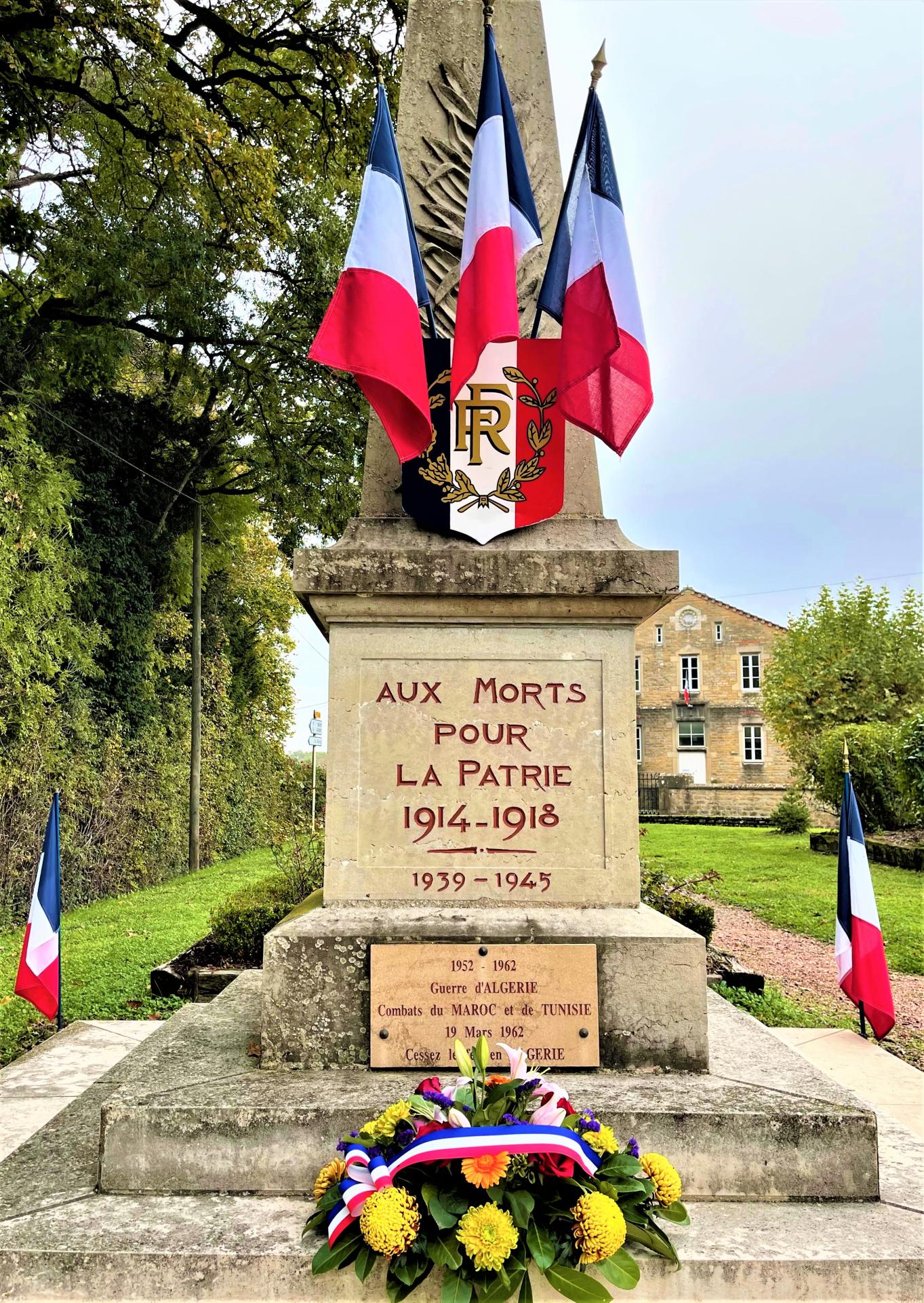 monument aux morts avec ses drapeaux tricolores et sa gerbe de fleurs